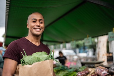 Man holding a bag of groceries at a greenmarket