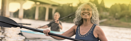 Two people in water holding canoe paddles and smiling