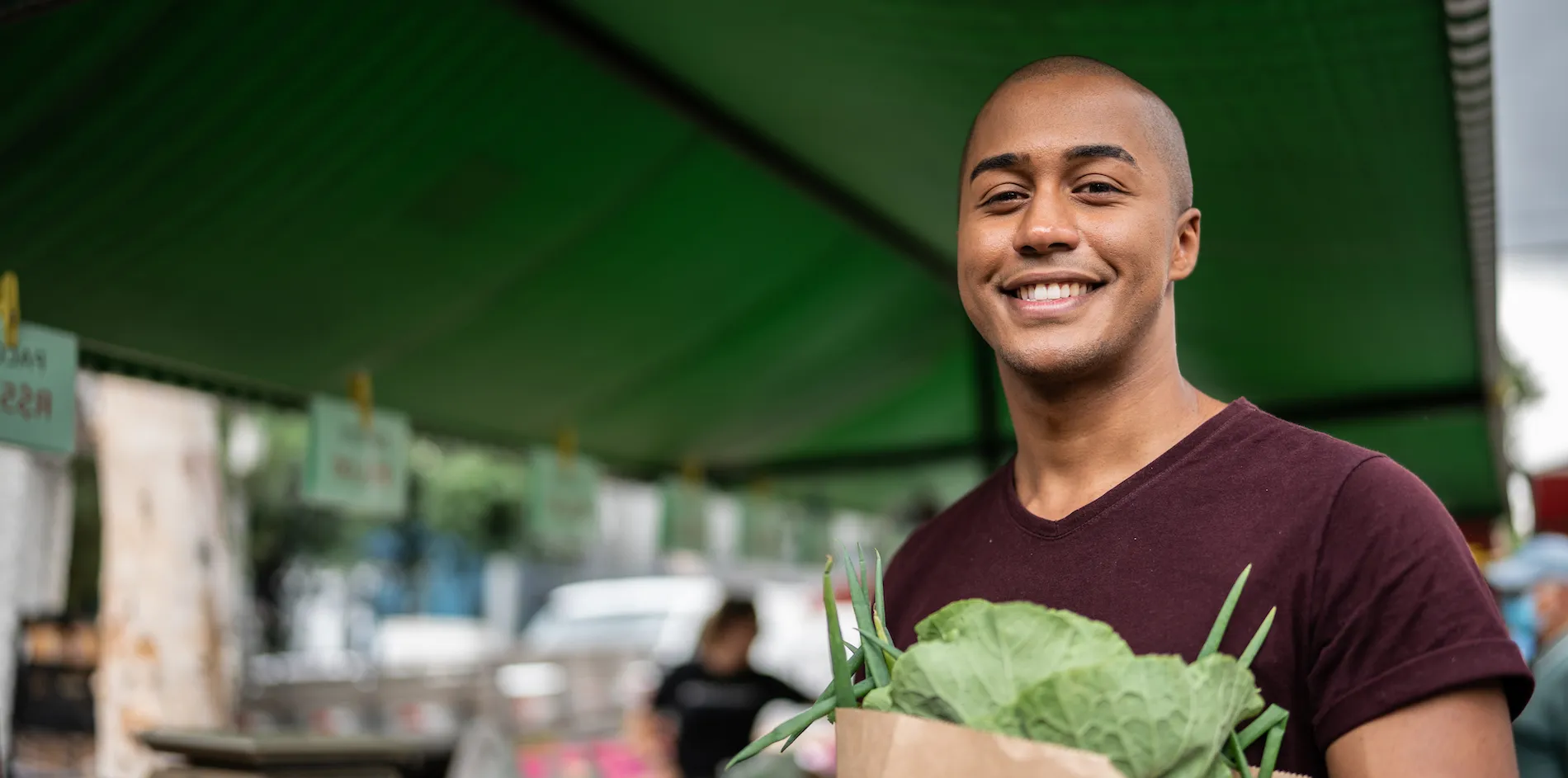Man holding a bag of groceries at a greenmarket