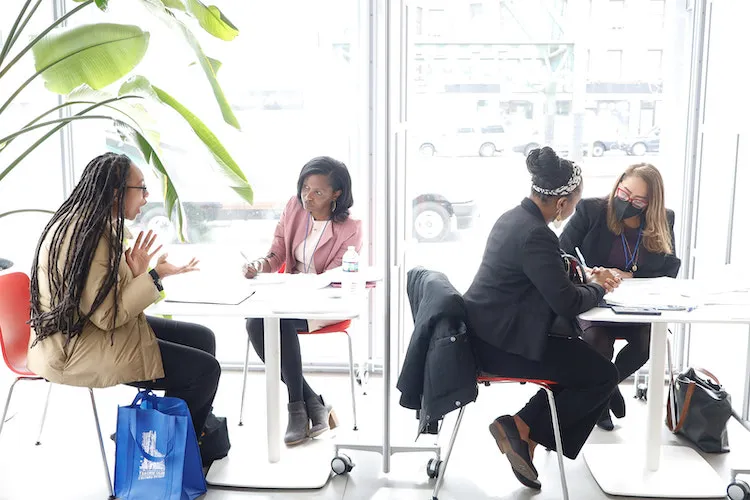 Two pairs of individuals sitting at tables and talking