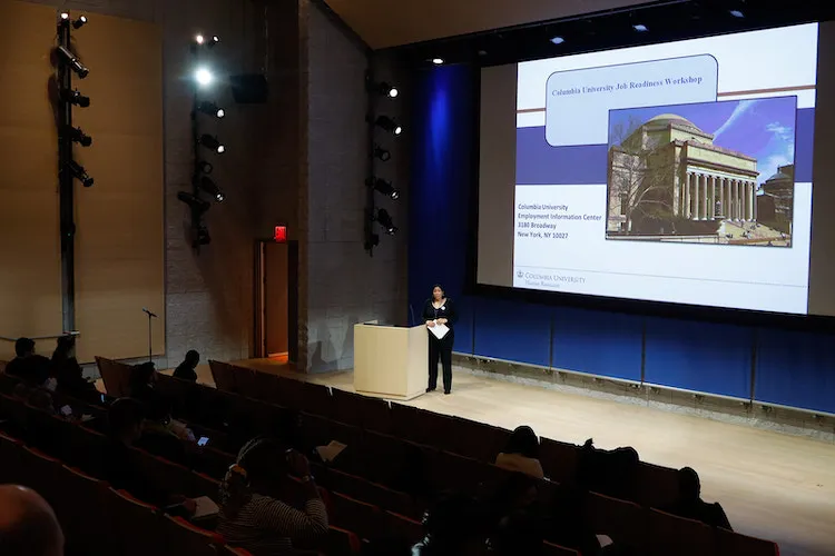 Photo of presenter standing at podium in auditorium