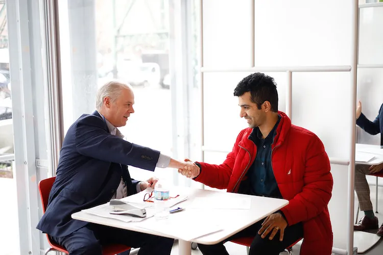 Two men sitting down and shaking hands